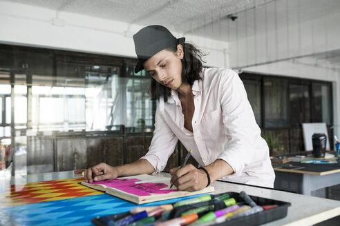 Künstler bei der Arbeit, Zeichnung in einem Notizbuch in seinem Loft-Atelier - SBOF01406