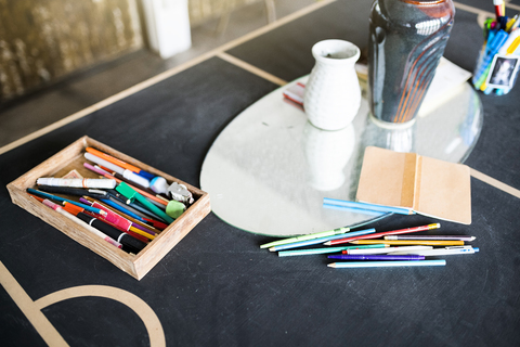 Buntstifte, Stifte und ein Notizbuch auf einem Tisch im Atelier eines Künstlers, lizenzfreies Stockfoto