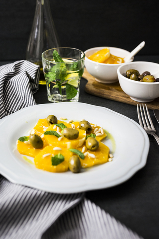 Salat mit Orangenspalten, Pinienkernen, grünen Oliven und Minzblättern, lizenzfreies Stockfoto