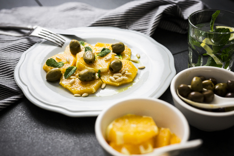 Salat mit Orangenspalten, Pinienkernen, grünen Oliven und Minzblättern, lizenzfreies Stockfoto