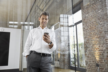 Mature businessman using smartphone in modern office - PDF01487