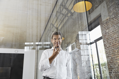 Mature businessman using smartphone in modern office stock photo