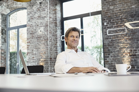 Portrait of mature businessman with laptop in modern office stock photo