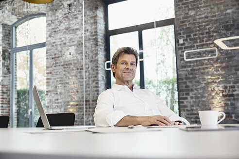 Porträt eines reifen Geschäftsmannes mit Laptop in einem modernen Büro - PDF01504