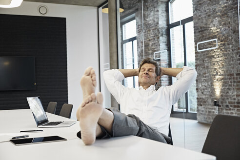Barefooted businessman relaxing in conference room of modern office - PDF01506