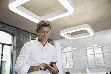 Mature businessman using smartphone in modern office - PDF01514