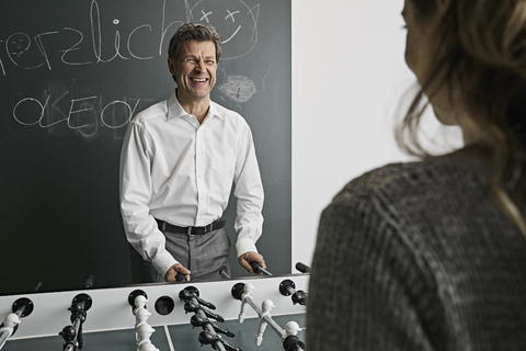 Businessman playing foosball with female colleague stock photo