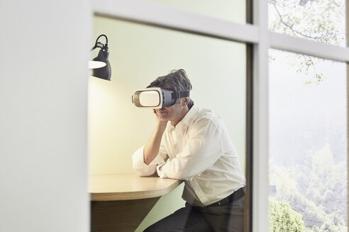 Businessman wearing VR glasses in modern office - PDF01538