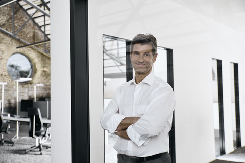 Porträt eines lächelnden reifen Geschäftsmannes in einem modernen Büro, lizenzfreies Stockfoto