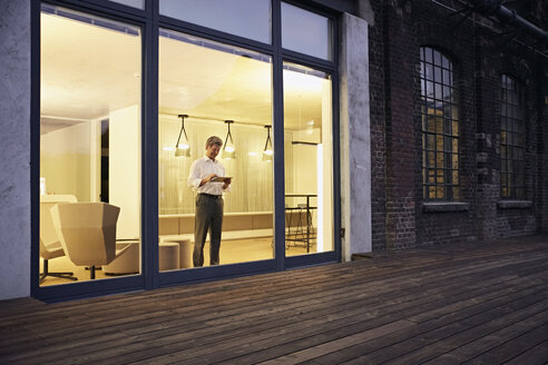 Exterior view of man using tablet in modern building at night - PDF01550