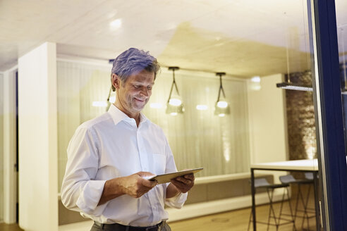 Mann benutzt Tablet in einem modernen Gebäude bei Nacht - PDF01551