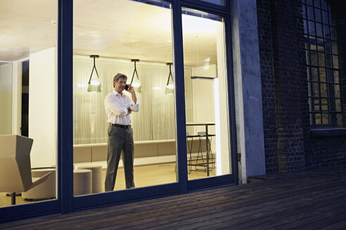 Exterior view of man using smartphone in modern building at night - PDF01552