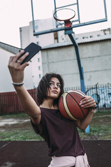 Junge Frau mit Basketball macht ein Selfie auf einem Platz im Freien - VPIF00335