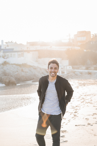 Portrait of laughing young man on the beach at twilight stock photo