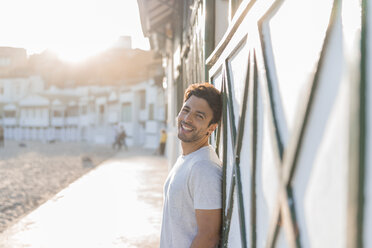 Porträt eines glücklichen jungen Mannes am Strand bei Sonnenuntergang - AFVF00140