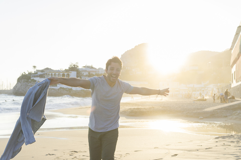 Portrait of happy young man dancing on the beach at sunset stock photo