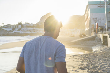 Back view of young man on the beach at sunset - AFVF00150