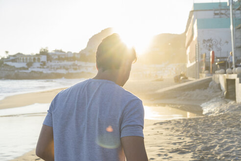 Rückenansicht eines jungen Mannes am Strand bei Sonnenuntergang - AFVF00150