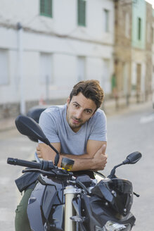 Porträt eines jungen Mannes auf einem Motorrad sitzend - AFVF00154