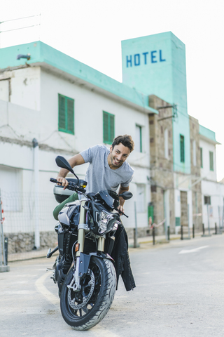 Porträt eines glücklichen jungen Mannes mit Motorrad, lizenzfreies Stockfoto
