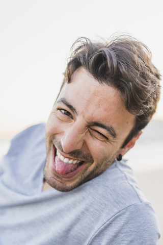 Portrait of winking young man stiking out tongue stock photo