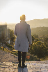 rückenansicht eines modischen jungen Mannes in grauem Mantel bei Sonnenuntergang - AFVF00173