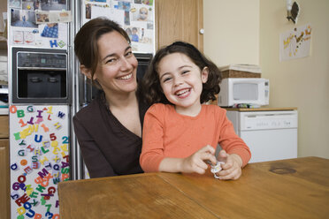 Portrait of a mother and daughter sitting at a kitchen table - FSIF02660