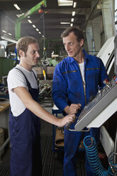 Two manual workers talking and working in a metal parts factory - FSIF02661