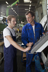 Zwei Arbeiter, die sich unterhalten und in einer Fabrik für Metallteile arbeiten - FSIF02661