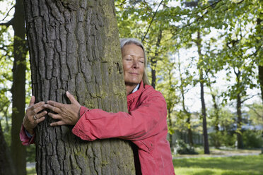 A senior woman hugging a tree - FSIF02673