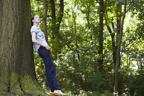 Eine junge Frau lehnt an einem Baum - FSIF02690