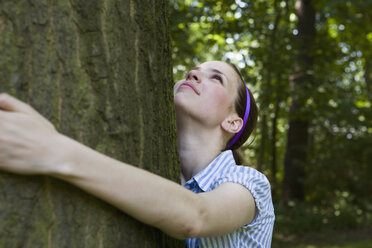 Eine junge Frau umarmt einen Baum - FSIF02692