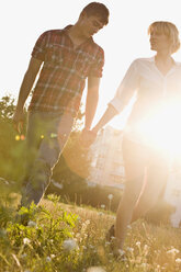 Ein junges Paar geht händchenhaltend durch einen Park, Vorderansicht - FSIF02738
