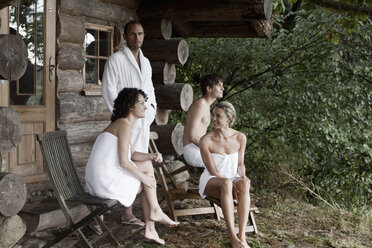 Four people relaxing outside the sauna at a health spa - FSIF02744