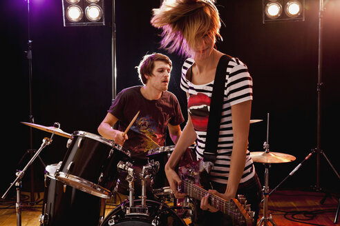 Ein Mann am Schlagzeug und eine Frau an der Gitarre in einer Rockband auf der Bühne - FSIF02758