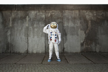 A saluting astronaut standing on a sidewalk in a city - FSIF02769