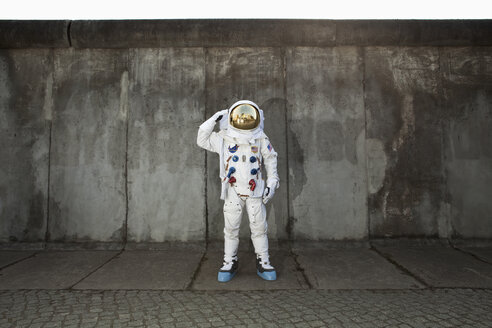 Ein grüßender Astronaut, der auf einem Bürgersteig in einer Stadt steht - FSIF02769