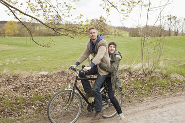 Ein Mann, der seine Freundin auf dem Fahrrad mitnimmt, auf dem Lande - FSIF02777
