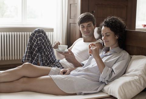 Ein Paar trinkt gemeinsam Tee im Bett, lizenzfreies Stockfoto