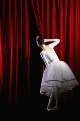 A ballet dancer peeking through a stage curtain, rear view - FSIF02808