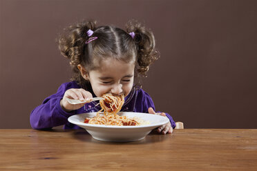 Ein junges Mädchen mit fest geschlossenen Augen isst Spaghetti, Studioaufnahme - FSIF02824