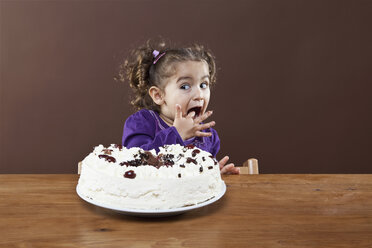 Ein junges Mädchen probiert heimlich eine Torte mit Zuckerguss, Studioaufnahme - FSIF02825