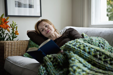 A woman reading a book while reclining on a sofa - FSIF02839