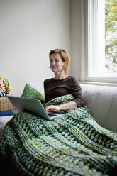 A woman reclining on a couch using a laptop - FSIF02841