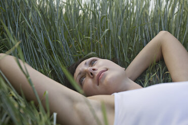 A woman lying in grass, day dreaming - FSIF02874