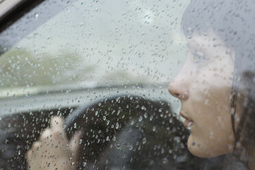 A woman driver sitting in car looking out window, raindrops on window - FSIF02876