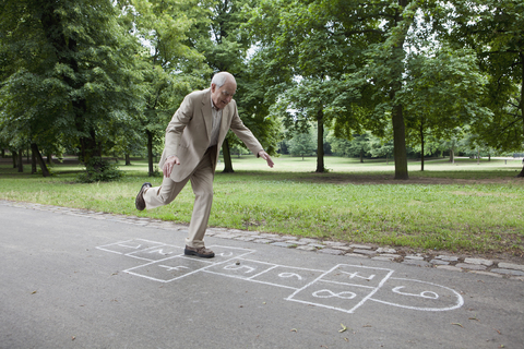 Senior man playing hopscotch in the park stock photo