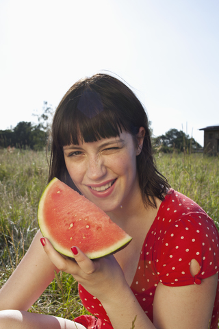 Mädchen im Feld sitzend mit einer Melonenscheibe in der Hand, lizenzfreies Stockfoto