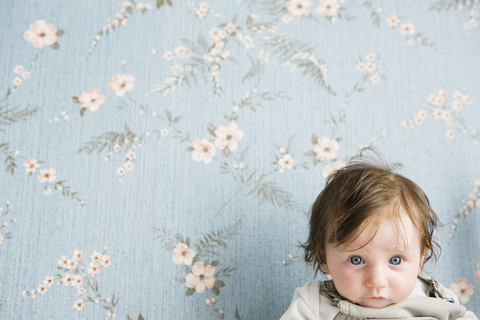 Portrait of a baby in front of floral wallpaper stock photo