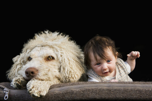 Ein Hund und ein Baby, die nebeneinander auf dem Bauch liegen - FSIF02918